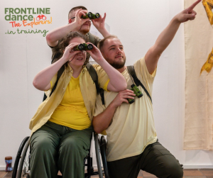 Three Explorers all grouped together two looking through their binoculars towards the top right and one pointing with a straight arm in the same direction. Beth is in her wheelchair, Connor is knelt down beside her. Ben is stood up behind them both. All are wearing different shades of yellow and green, with backpacks on.