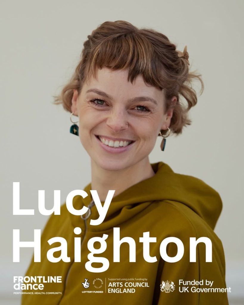 Lucy, is a white female with short hair and fringe who is standing sideways on and smiling. She is wearing a mustard yellow zip up hoodie and has dangling gold hoop earrings with green semi circles attached to the bottom. Overlaid the image is the text “Lucy Haighton’ and FRONTLINEdances, Art Council England and Funded by UK Government logos in white.