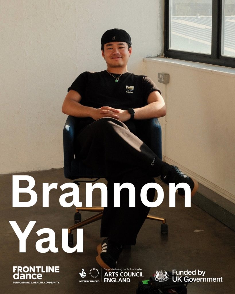 Brannon is an asian male who is leaning back in a bucket chair with wheels in a white studio space and smiling. He is wearing a cap with the peak at the back, black tshirt and trousers with black adidas trainers. Overlaid the image is the text “Brannon Yau” and FRONTLINEdance, Art Council England and Funded by UK Government logos in white.